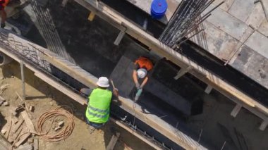 Yüksek katlı bir konut inşaatı sürüyor ve işçiler sıkı çalışıyor.