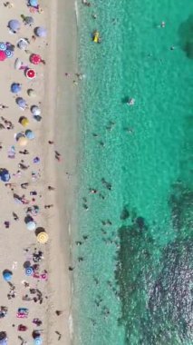 Dikey Video: Parlak gök mavisi dalgaları el değmemiş beyaz kumla buluşuyor.