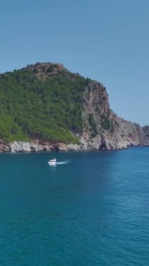 Dikey Video: Beyaz yatlar kıyı kenarında seyrederken, turistler manzaranın keyfini çıkarıyor.
