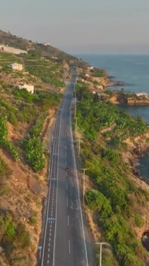 Dikey Video: Gün batımında okyanus manzaralı manzaralı manzaralı manzaralı bir sahil yolculuğu.
