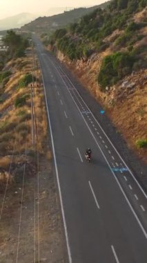 Dikey Video: Altın gün batımında sahil boyunca hızlı bir motosiklet yolculuğu.