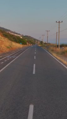 Dikey Video: Parlayan bir günbatımı bir motosikletçi sahil gezisini aydınlatıyor.