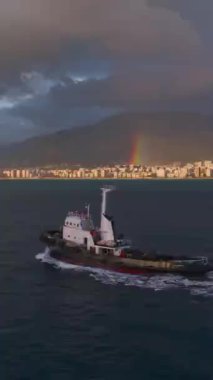 Römorkör limana canlı bir gökkuşağı ve gün batımı renkleriyle gider..