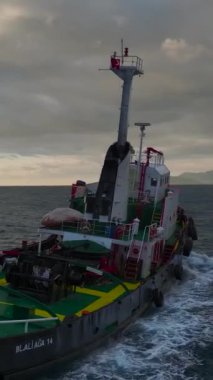 Bir deniz çekişi, çarpıcı bir günbatımının büyük bir gökkuşağıyla buluşması gibi limana doğru ilerliyor..