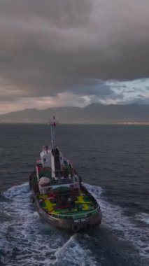 Bir römorkör, parlak bir gökkuşağıyla sihirli bir günbatımının altında limana yaklaşıyor..