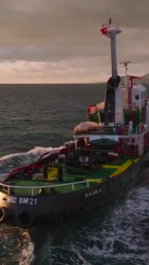 Bir römorkör, kızgın bir günbatımında gökkuşağı gibi limana doğru yol alır..