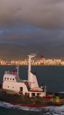 Bir römorkör parlayan günbatımının altında limana doğru süzülüyor ve gökkuşağını vuruyor..