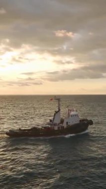 Römorkör gün batımının ve kalın gökkuşağının altında limana doğru yol alıyor..