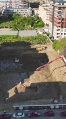 Çalışanların ve makinelerin faaliyet gösterdiği hareketli bir inşaat sahası.