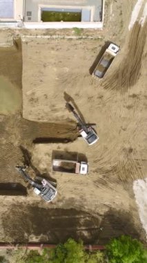 İşçilerin ve makinelerin yeni bir binanın temelini hazırladığı yoğun bir site..