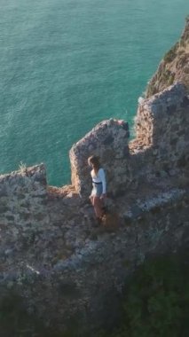 Bir model, mavi deniz manzaralı bir uçurumda mükemmel bir zemin gibi duruyor..