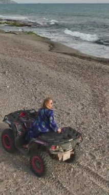 Güzel bir model, parlayan deniz kıyısında dörtlü bisiklete binmekten zevk alır..