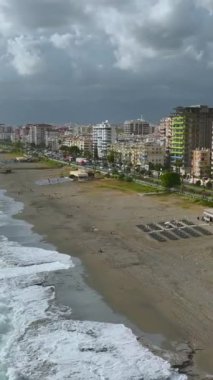 Yoğun turkuaz dalgalar fırtınalı gökyüzünün altında kıyı şeridini vurdu..