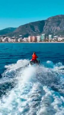 Dikey Video: Bir kız heyecan verici bir jet ski yolculuğunda denizde su sıçratıyor.