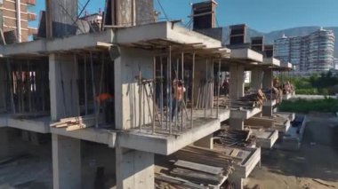 İşçilerin ve makinelerin yüksek binalar inşa ettiği işlek bir inşaat alanı.