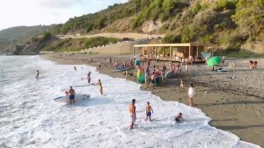 Beyaz kumda yatan modeli izleyin, turkuaz deniz kenarında güneşin tadını çıkarın..