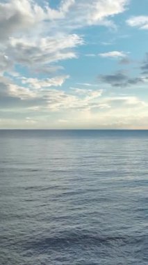 Sakin deniz dalgaları üzerinde renkli bulutlarla dramatik bir akşam göğü..