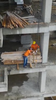 Vinçler ve işçiler bir inşaat projesinde malzeme taşıyorlar.