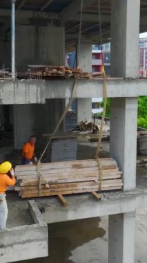 Vinçler ağır yükleri kaldırırken inşaatçılar aşağıda koordine ediyor.