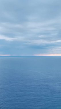 Yumuşak dalgalar ve ufka uzanan deniz dokularıyla huzurlu mavi bir günbatımı..