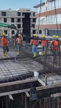 İşçiler inşaat alanına aktif olarak beton döküyorlar.