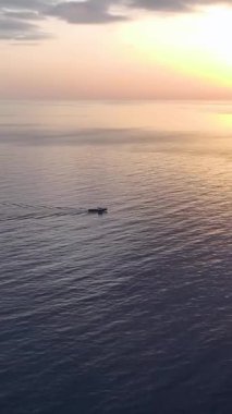 Gün batımında sakin dalgalarla bir tekne limana yaklaşıyor..