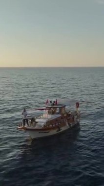 Gün batımının renkleri dingin bir tekne ve şehir manzarasını aydınlatıyor.