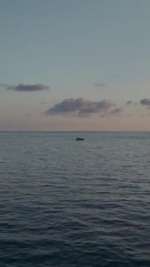 Gün batımının renkleri dingin bir tekne ve şehir manzarasını aydınlatıyor.