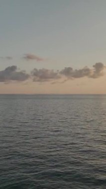 Balıkçı teknesi, gün batımı ve şehir manzaralı sakin bir deniz..