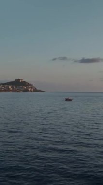 Huzurlu günbatımı sahnesi Bir tekne ve parlayan şehir arkaplanı.