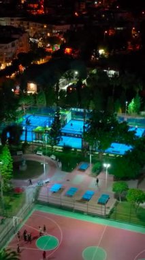 Açık bir gökyüzünün altında canlı bir gece raketi tenis oyunu.