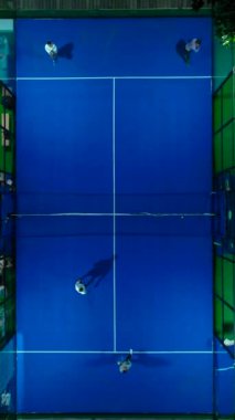 Dikey Video: Paddle tenis kortları parlak ışıklar ve açık gökyüzü altında aktif antrenman yapan oyuncularla canlı gece oyunlarına ev sahipliği yapıyor.