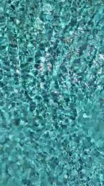 Gök mavisi suyu ve güneş ışığı altında rahatlatıcı jakuzi kabarcıkları olan sakin bir havuz..