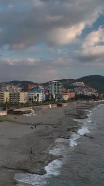 Deniz yavaşça kayalık kıyıya köpüklü dalgalarla dokunuyor..