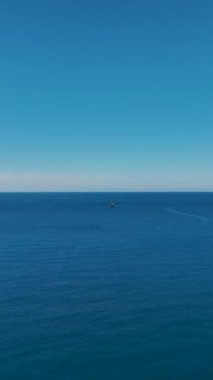 Uzaklarda bir gemiyle huzurlu bir deniz manzarası..