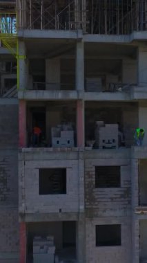 İşçiler inşa ederken mühendisler planları kontrol ediyor. Ayrıntılı ve yoğun bir projenin hava görüntüleri.