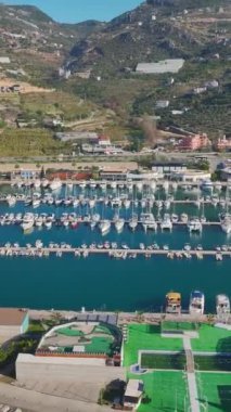 Yatlar ve köpüklü deniz. Sakin ve çarpıcı bir limanın havadan görünüşü.