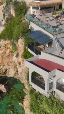 Gök mavisi suları olan bir uçurum restoranı. Sakin ve zarif bir kıyı bölgesinin hava görüntüleri..