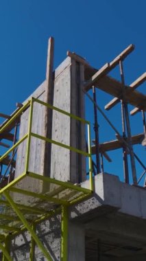 İşçiler Duvarları Birleştirirken ve Metal Çerçeve Kurarken Bir Crane Taşıyıcı Ağır Malzemelerin Dikey Videosu