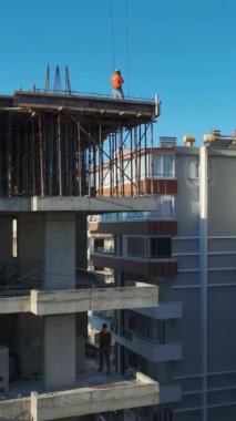 Turna kaldırma ve duvar örme işçileri. Ayrıntılı ve üretken bir inşaat ortamının hava görüntüleri.