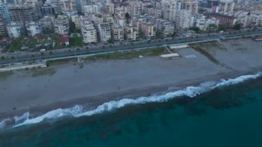 Hava Videosu: Akşam ışığında parlayan şehir manzarası ile gök mavisi denizde çarpıcı günbatımı yansımaları