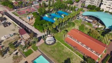 Bir akademide profesyonel bir raket tenis kortunun havadan görünüşü, oyuncular heyecan verici bir maçta topa koşuyorlar..