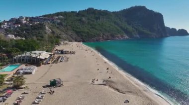 Düşük mevsimde, el değmemiş kum ve güneşin altında hafif dalgaları gösteren huzurlu ve boş bir kumsalın hava görüntüleri..