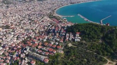 Sahil boyunca uzanan temiz mavi su ve bulutsuz gökyüzü ile çevrili bir şehrin insansız hava aracı görüntüsü..
