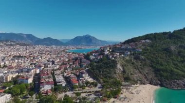 Etrafı denizle çevrili, yüksek binaları ve bulutsuz gökyüzü olan bir şehrin hava görüntüleri..