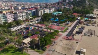 Sahil kenarındaki spor sahalarının, kortların, fitness ekipmanlarının ve okyanus kenarında egzersiz yapan insanların robot görüntüleri..