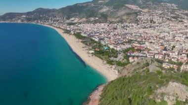Parlak mavi gökyüzünü yansıtan şeffaf suyu olan güzel beyaz bir kumsalın insansız hava aracı görüntüleri..