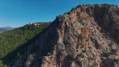 Alanya 'nın kayalık bir tepedeki ortaçağ kalesinin havadan çekilmiş görüntüleri, aşağıdaki mavi okyanus ve şehrin muhteşem manzarasını sunuyor..
