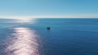 Yelkenli uzun bir korsan gemisinin insansız hava aracı görüntüleri sakin okyanusta tarihi bir limana doğru süzülüyor..