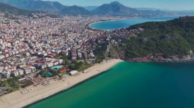 Güneşli bir günde güzel bir sahil, sakin dalgalar ve rahatlatıcı bir atmosferi olan Alanya 'nın sahil manzarası..